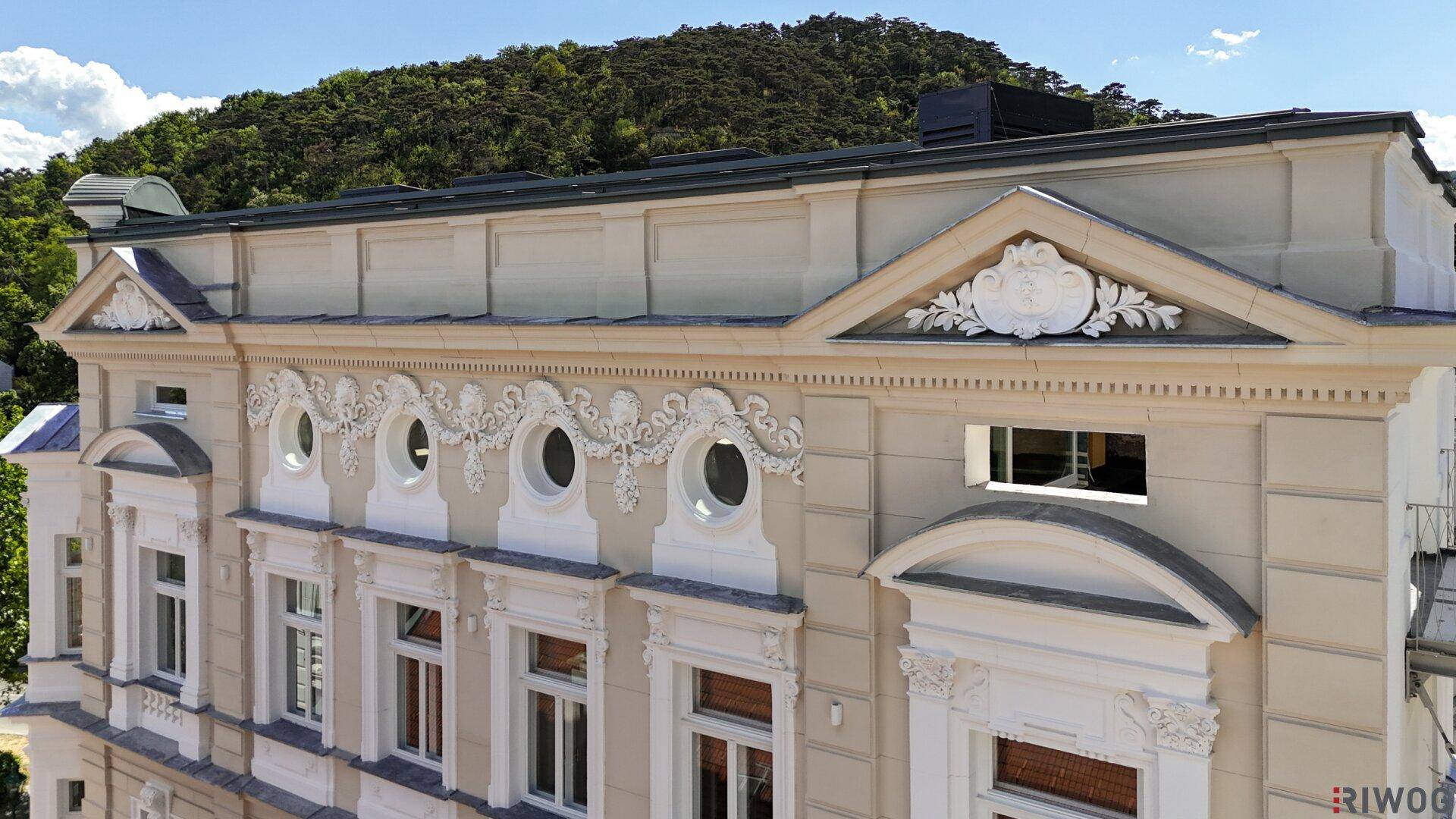 Detailansicht der eleganten Fassade eines historischen Gebäudes mit reichen Verzierungen und runden Fenstern.