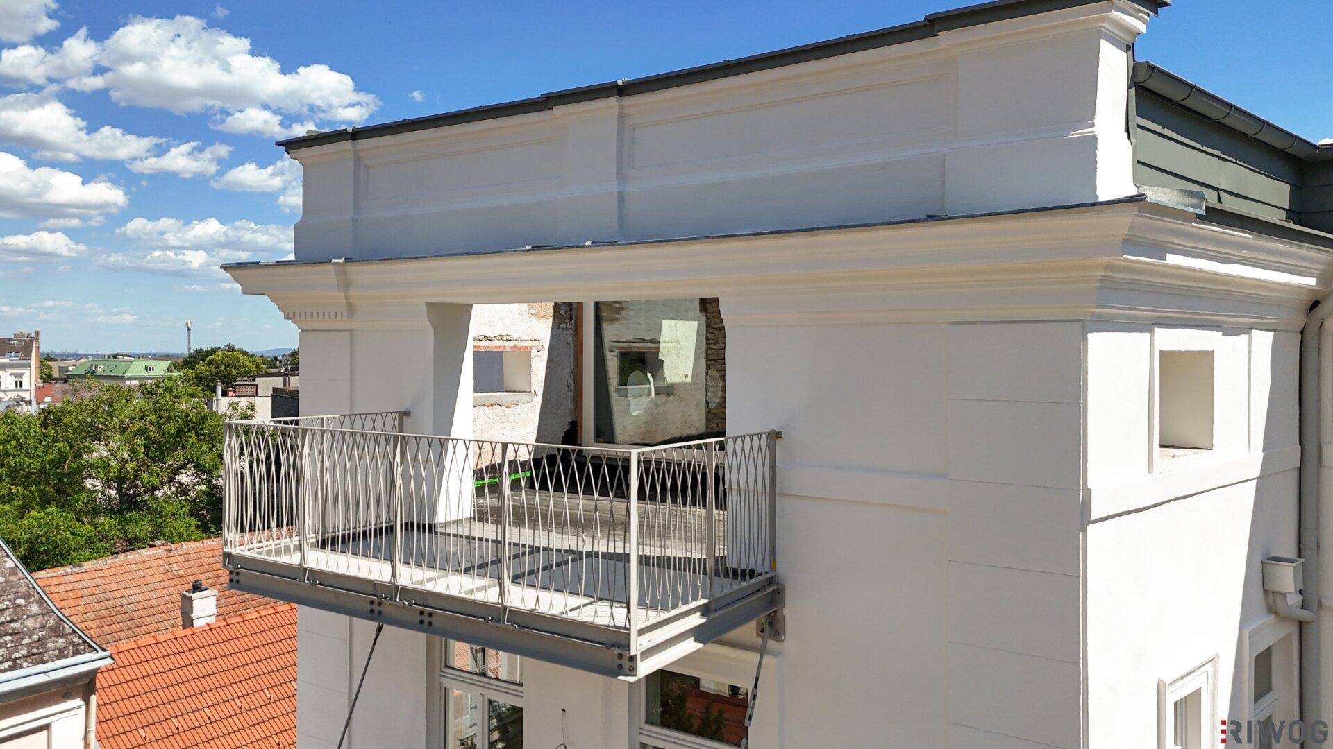 Unfertiger Balkon mit modernem Metallgeländer und Blick auf die Dächer der Stadt.