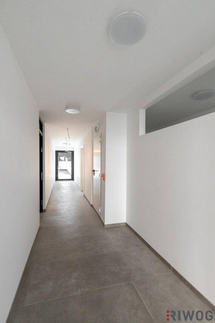 Heller, moderner Flur mit grauen Fliesen und Zugang zu den Wohneinheiten.