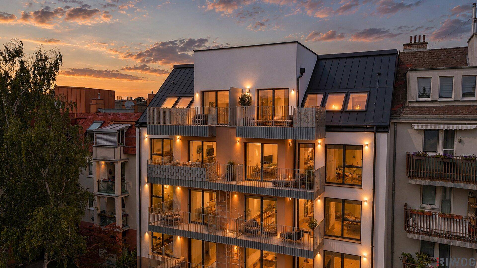Moderne Wohnfassade mit Balkonen und großen Fenstern bei Sonnenuntergang.