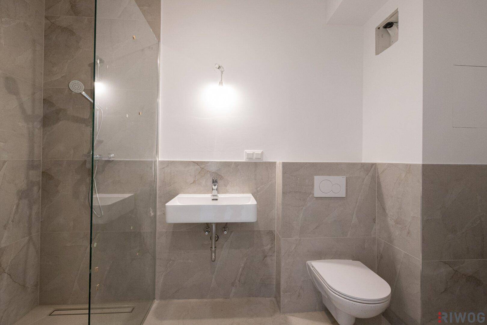 Modernes Badezimmer mit begehbarer Dusche, Wand-WC und grauen Fliesen.
