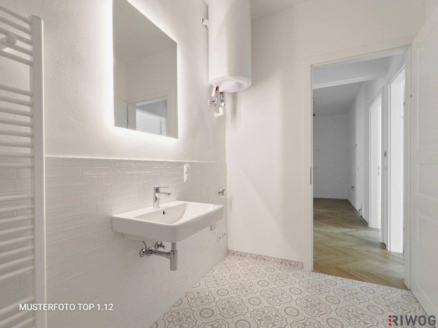 Helles Badezimmer mit Waschbecken, beleuchtetem Spiegel und beheiztem Handtuchhalter.