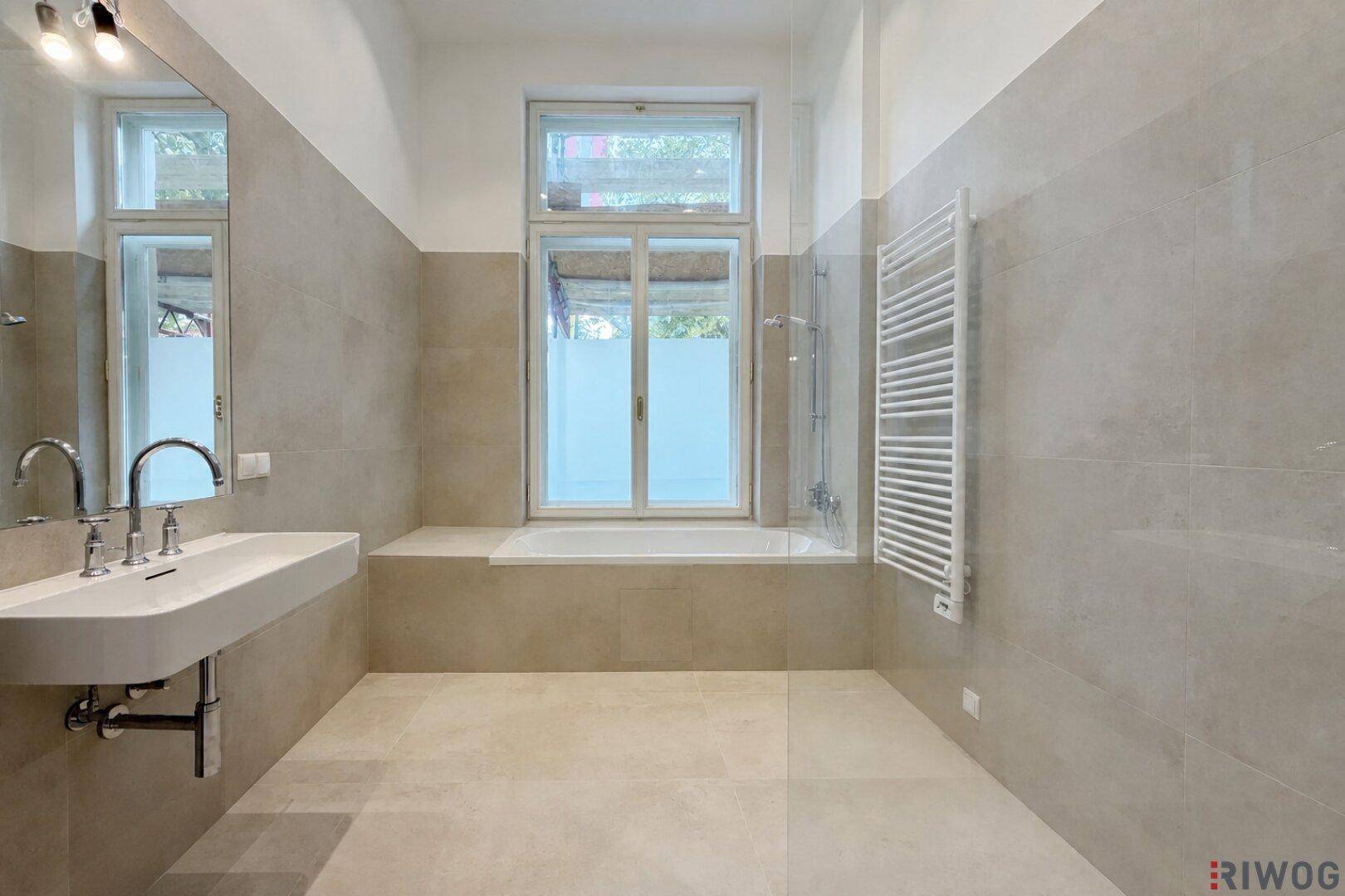 Modernes Badezimmer mit Badewanne, Dusche, Einzelwaschbecken, beheiztem Handtuchhalter und Fenster.
