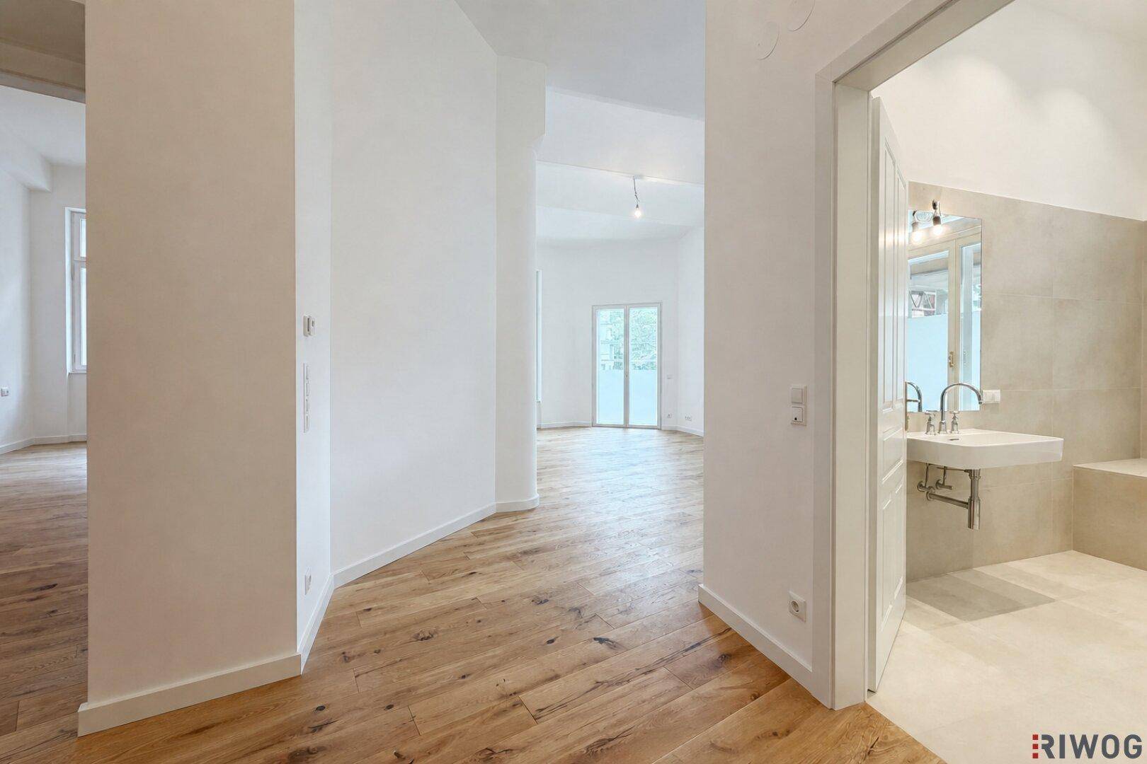 Heller Flur mit Holzboden, der zu weiteren Räumen und einem modernen Badezimmer führt.