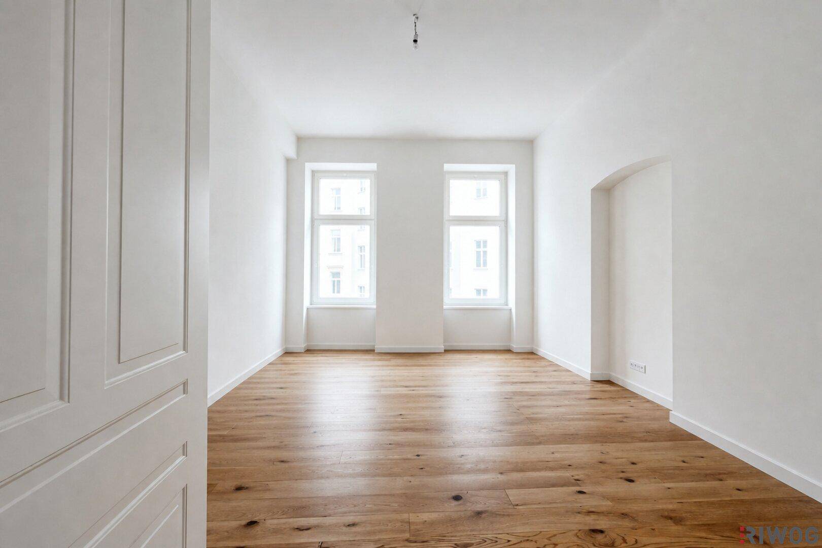 Ruhiges Schlafzimmer mit Holzdielenboden und zwei großen Fenstern, bietet viel Tageslicht.