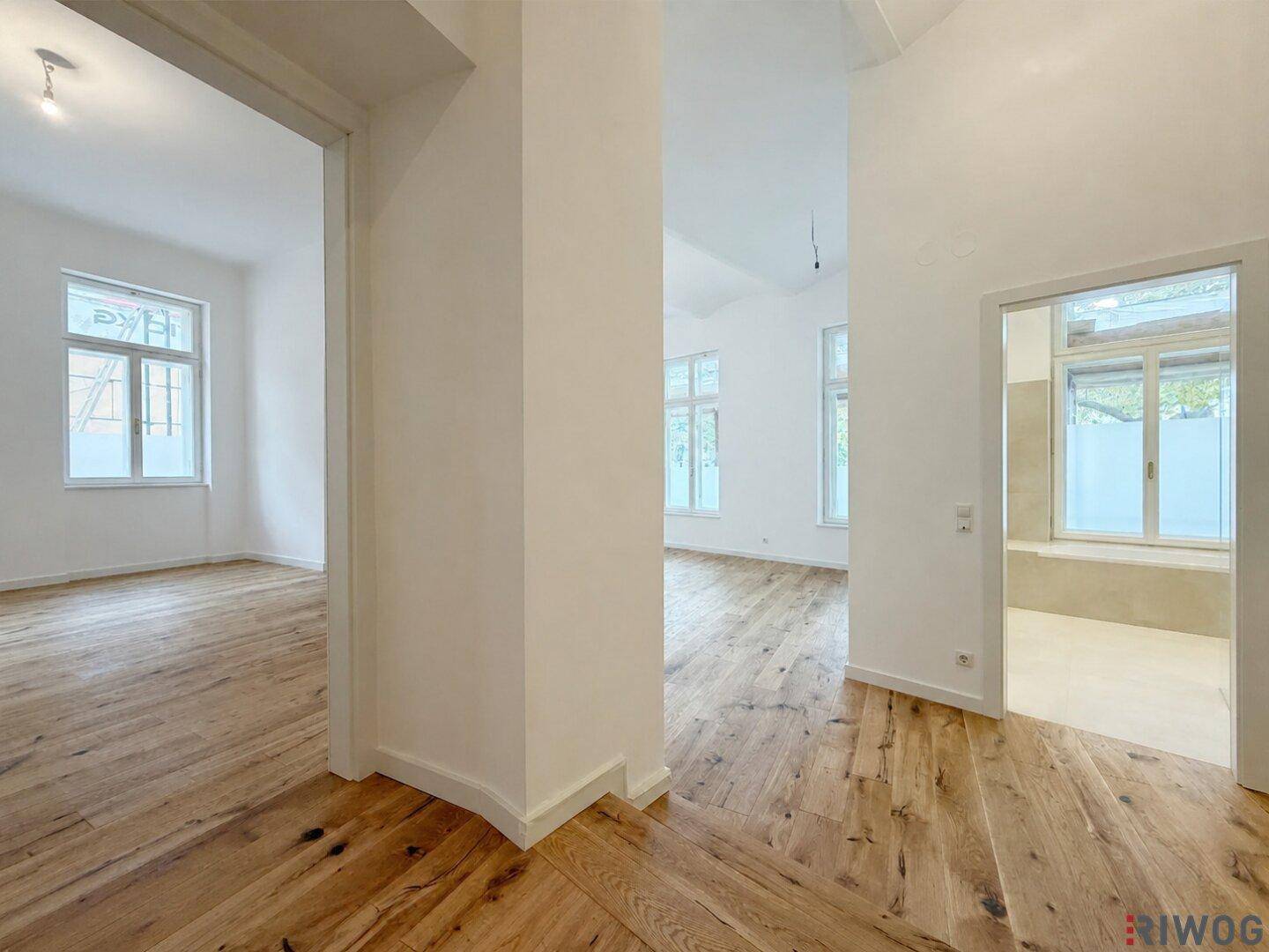 Geräumiger Flur mit Holzdielenboden, der zu verschiedenen hellen Zimmern und dem Badezimmer führt.