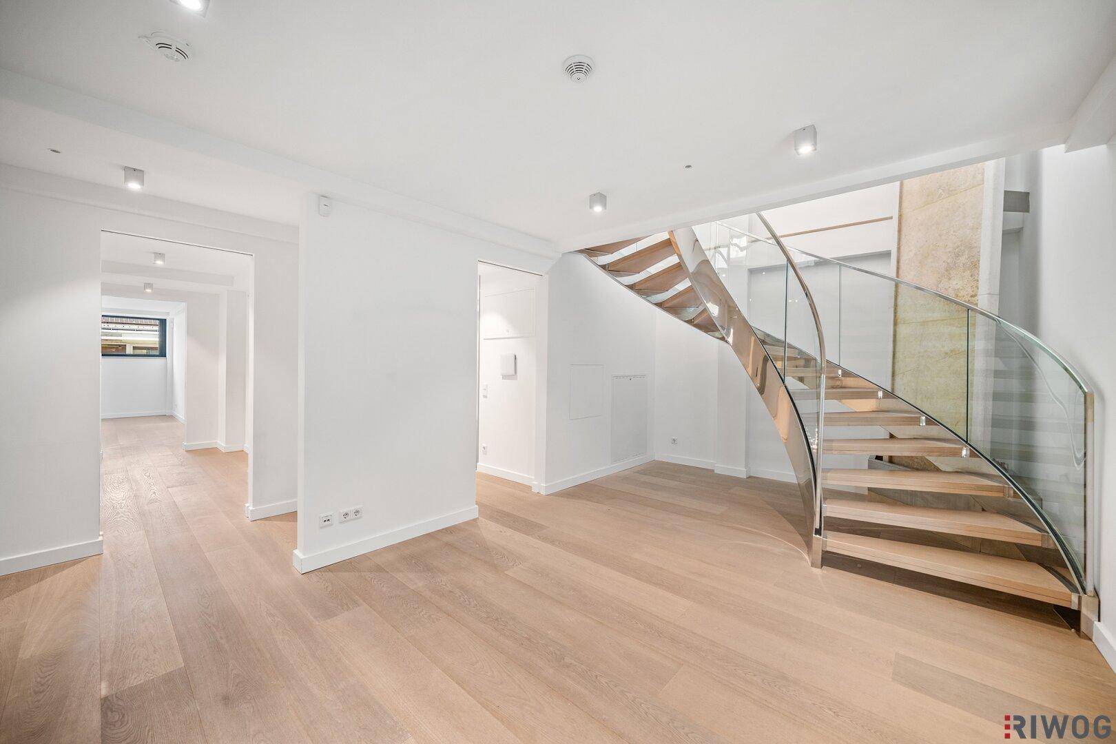 Eleganter Eingangsbereich mit moderner Wendeltreppe aus Holz und Glasgeländer.
