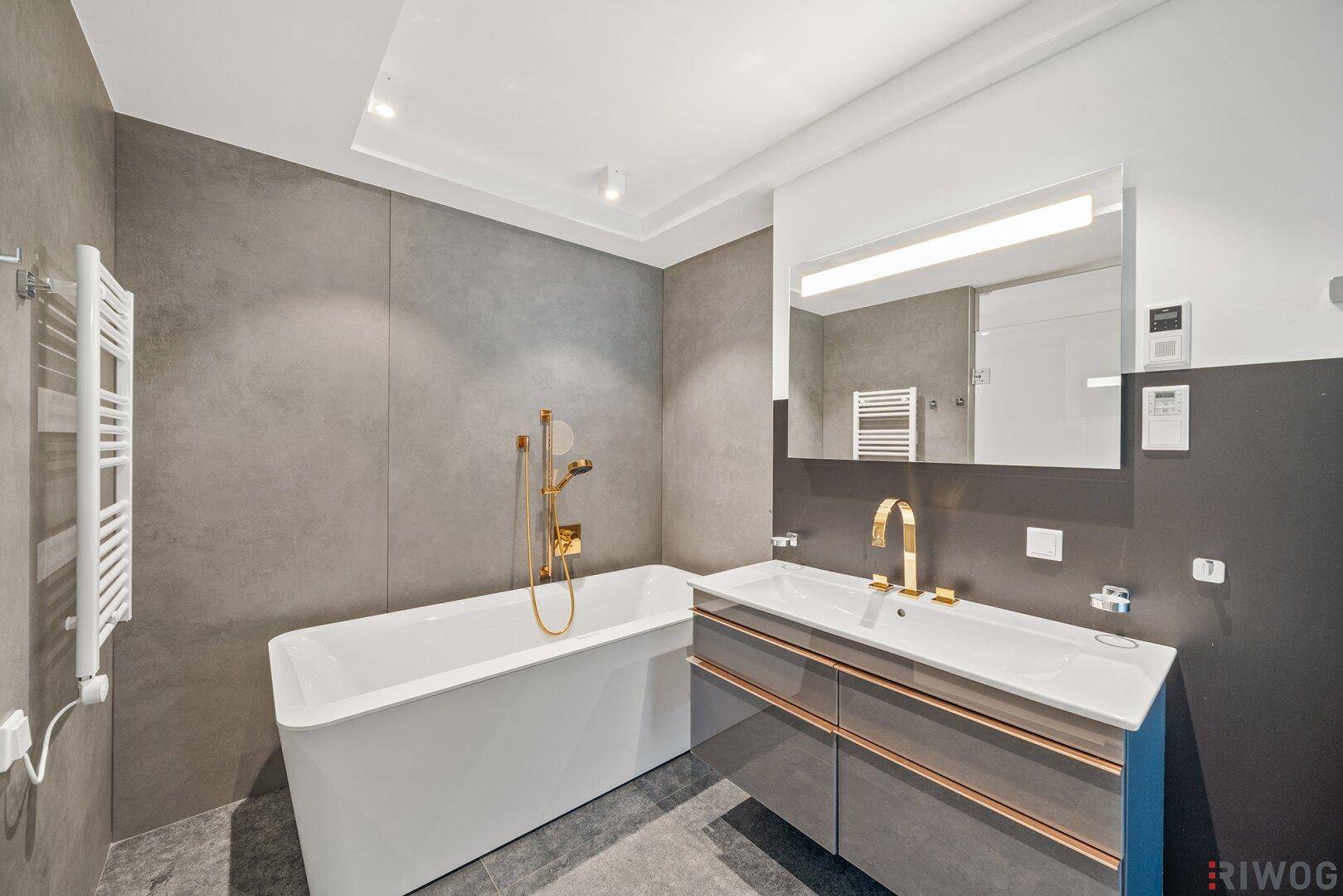 Modernes Badezimmer mit freistehender Badewanne, Einzelwaschbecken und eleganten Armaturen.