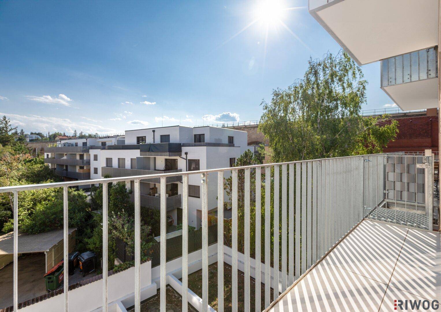 Weitblick vom Balkon über die Nachbarschaft mit modernen Wohngebäuden unter blauem Himmel.