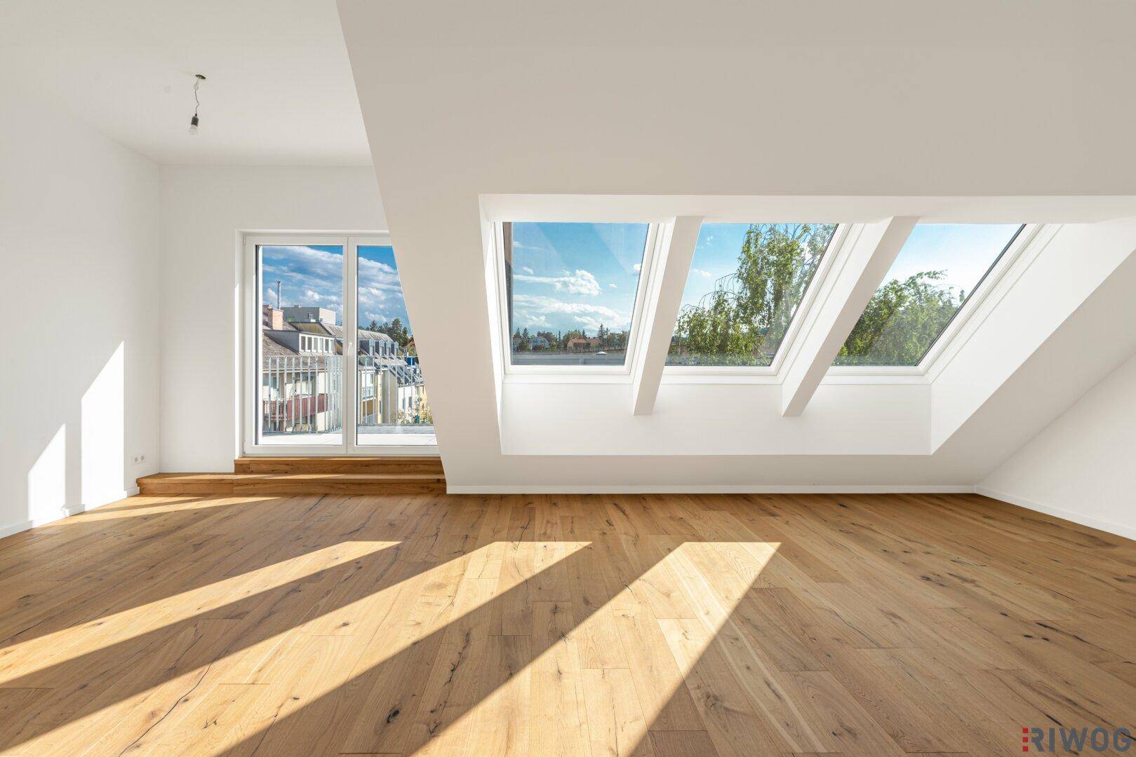 Heller Wohnraum im Dachgeschoss mit großen Dachfenstern, Holzboden und viel natürlichem Licht.