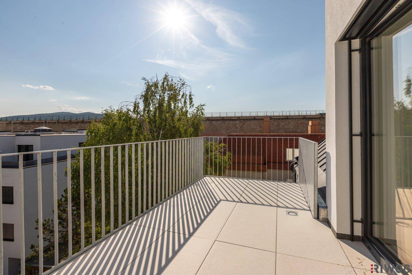 Heller Balkon mit Fliesenboden und Metallgeländer, bietet einen weiten Blick auf die Umgebung.