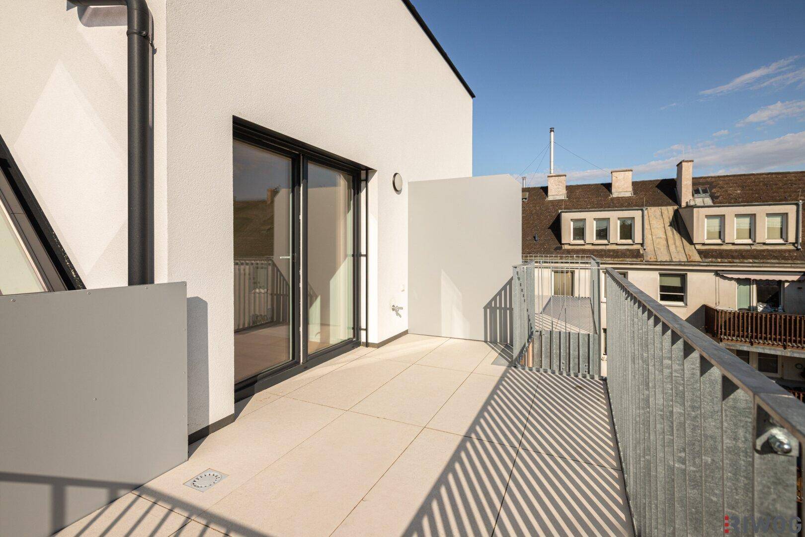 Balkon mit Fliesenboden und Metallgeländer, bietet einen Blick auf die umliegenden Gebäude.