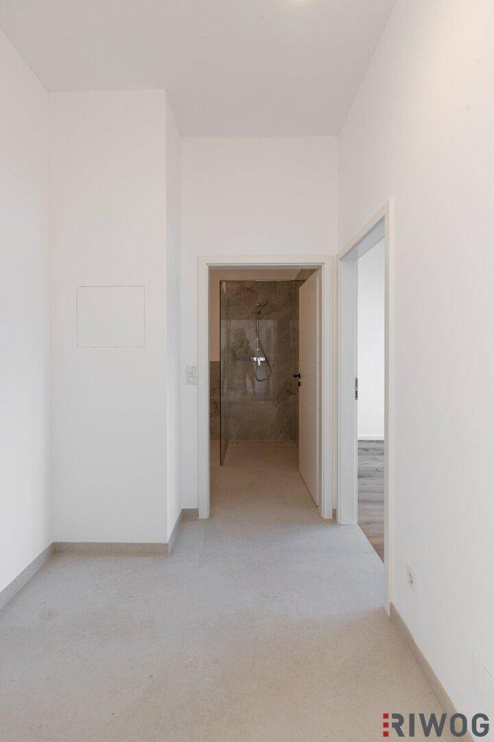 Heller Flur mit Fliesenboden, der zu weiteren Räumen und einem Badezimmer führt.