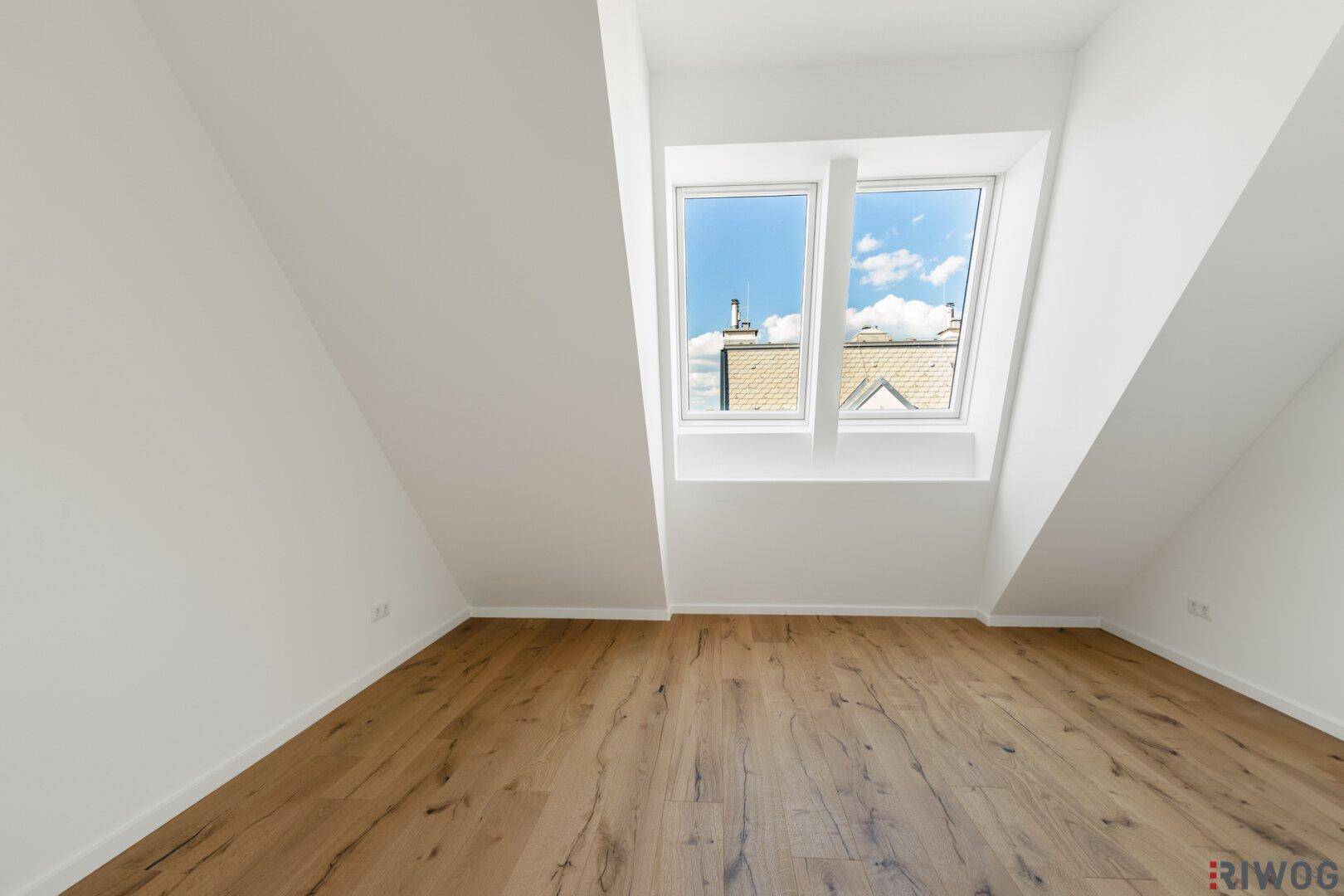 Geräumiges Schlafzimmer im Dachgeschoss mit Holzboden und zwei großen Dachfenstern für viel Licht.