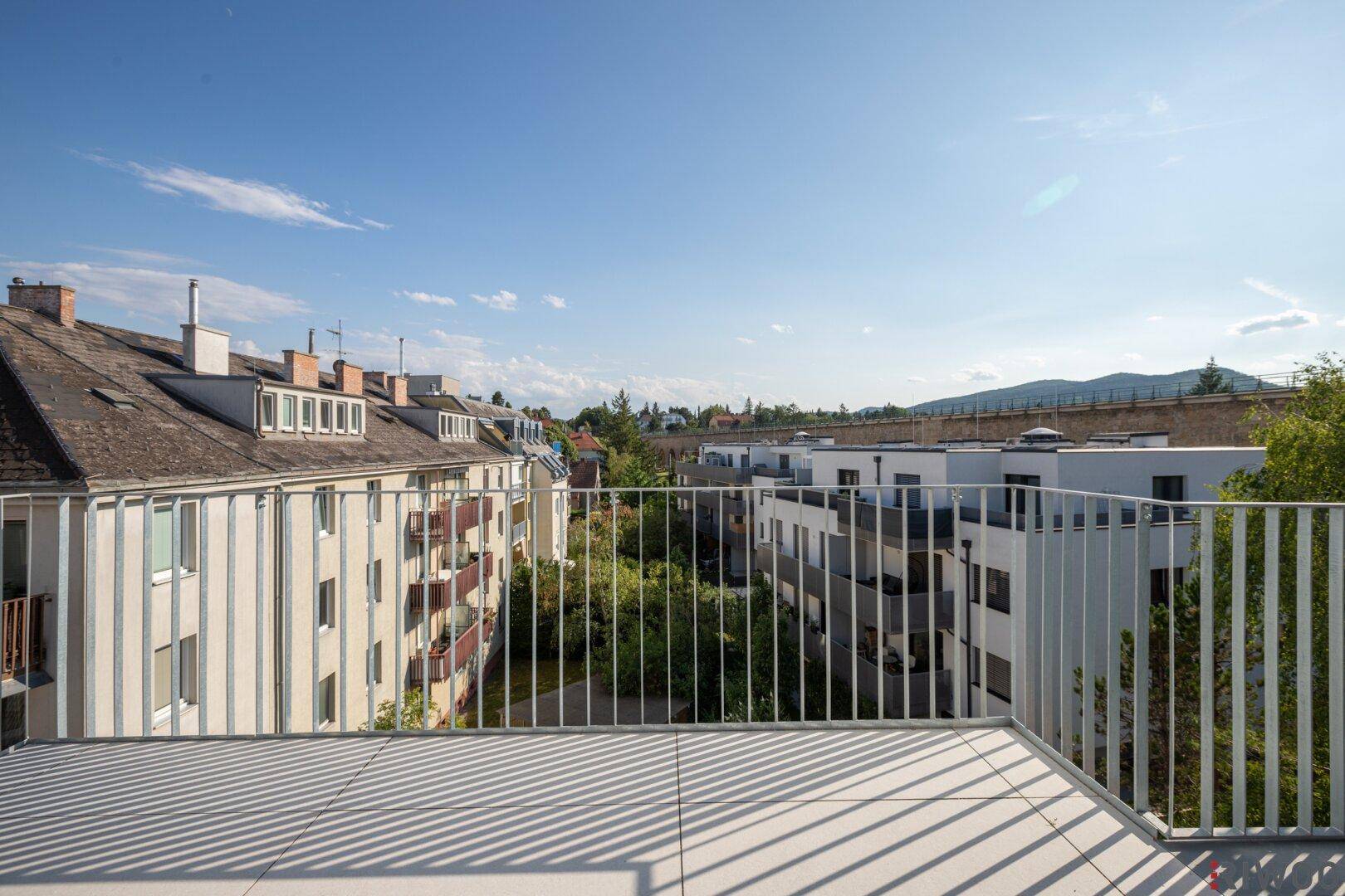 Weitläufiger Ausblick von einem Balkon auf die Nachbarschaft und die grüne Umgebung.