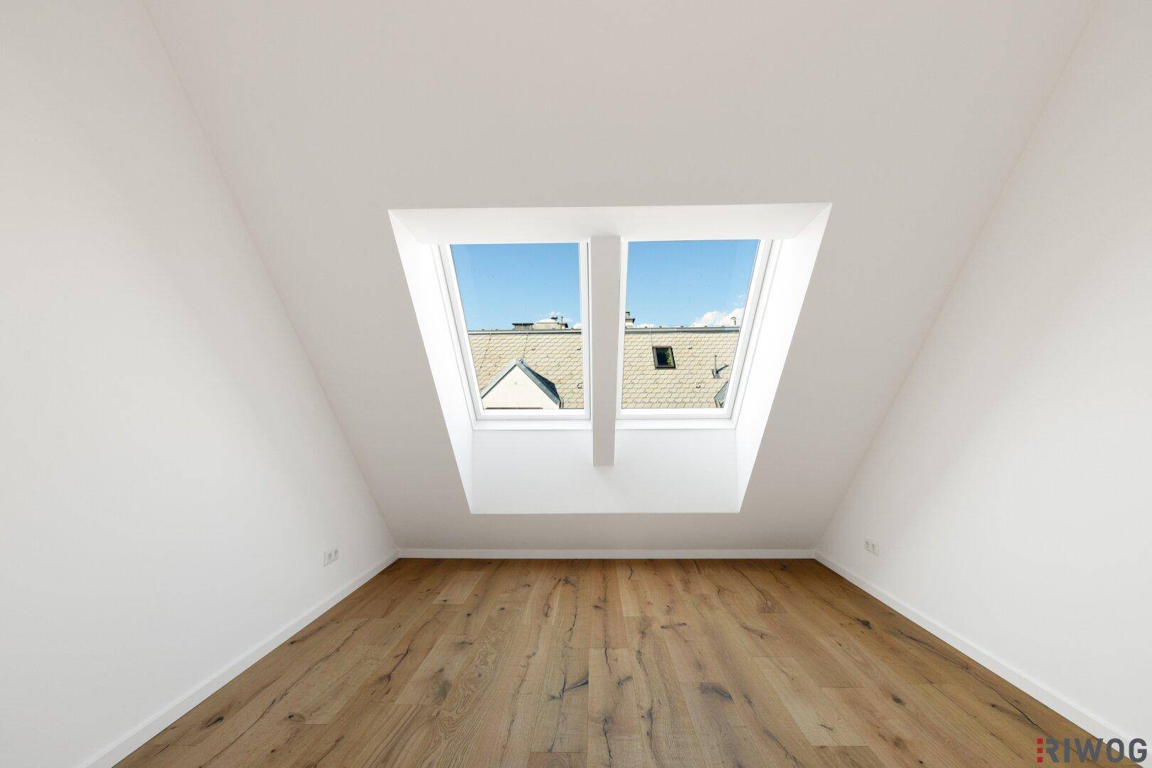 Geräumiger Raum im Dachgeschoss mit Holzboden und schrägen Wänden, ideal für individuelle Gestaltung.