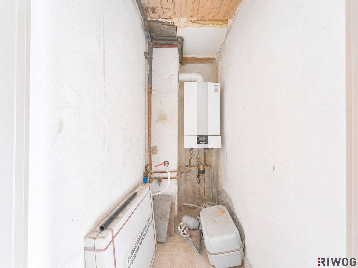 Kleiner Hauswirtschaftsraum mit Heizungsanlage und sichtbaren Rohren.