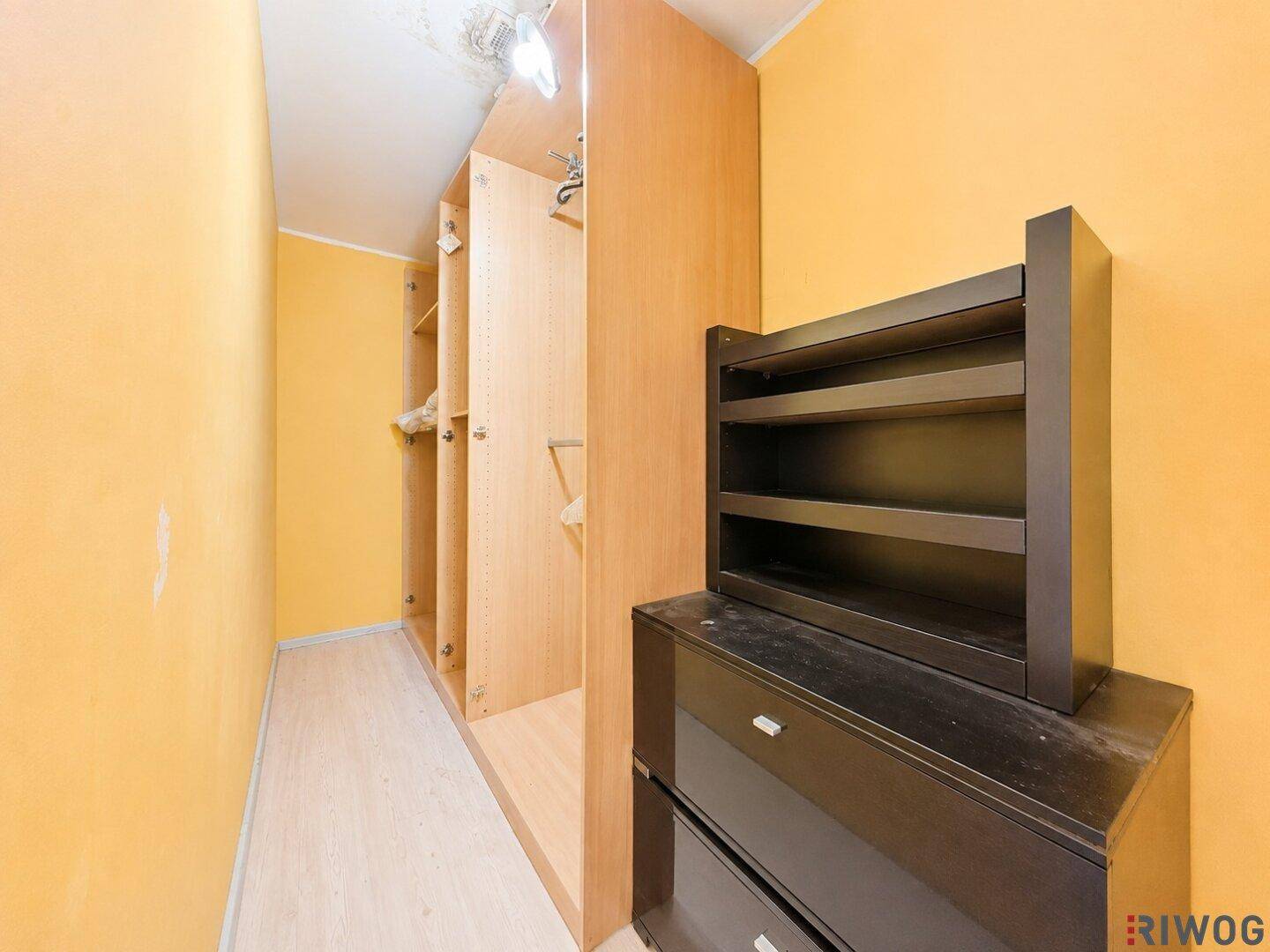 Begehbarer Kleiderschrank mit Holzregalen und gelben Wänden.