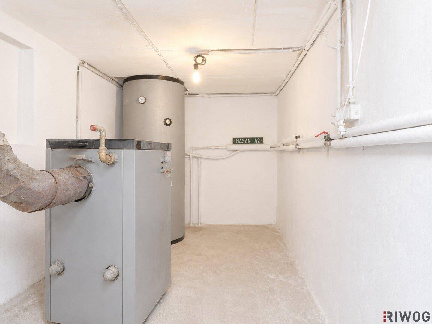 Heizungsraum mit Warmwasserspeicher und sichtbaren Rohrleitungen, funktional und geräumig.