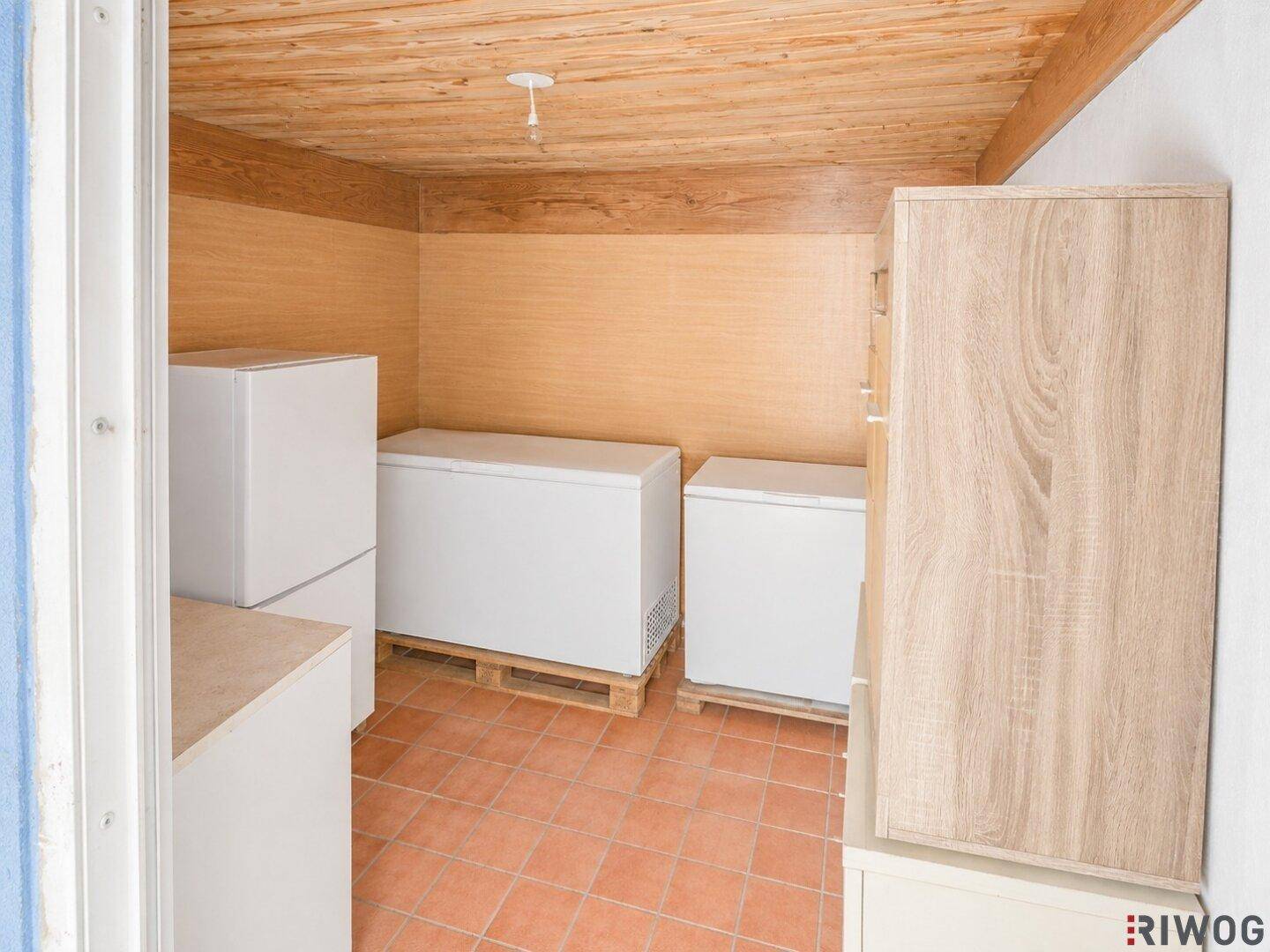 Praktischer Abstellraum mit mehreren Gefriertruhen und Holzschränken, ideal für Vorräte.