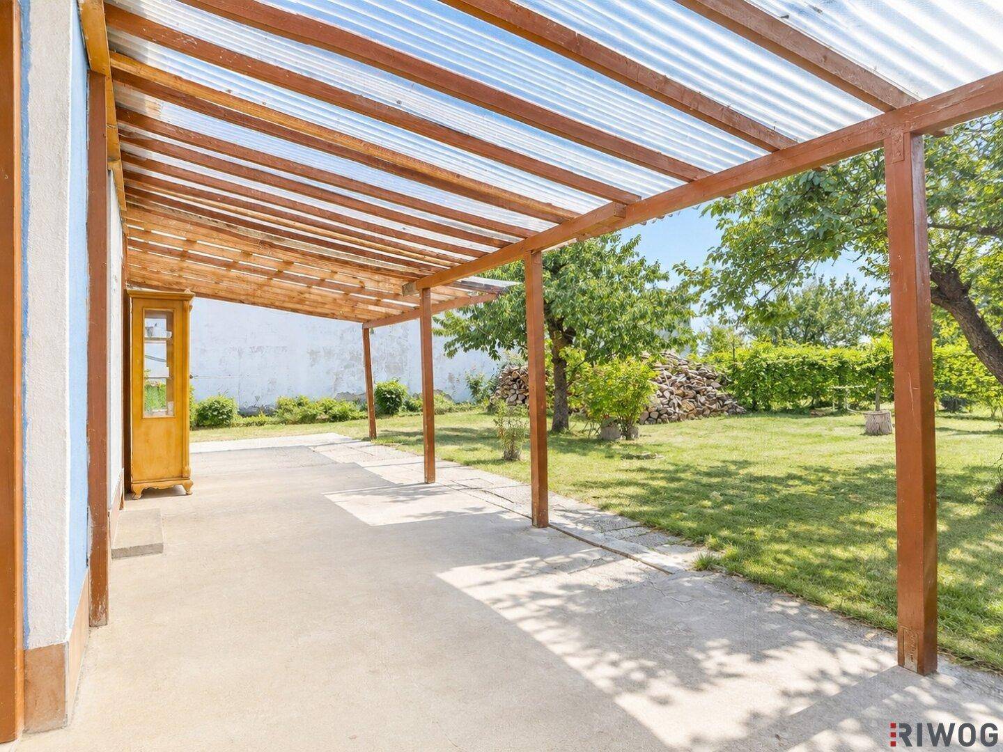 Überdachte Terrasse mit Betonboden und Blick auf den grünen Garten, ideal zum Entspannen.
