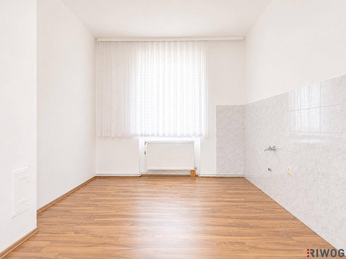 Leerer Raum mit Laminatboden und gefliester Wand, bereit für individuelle Gestaltung.