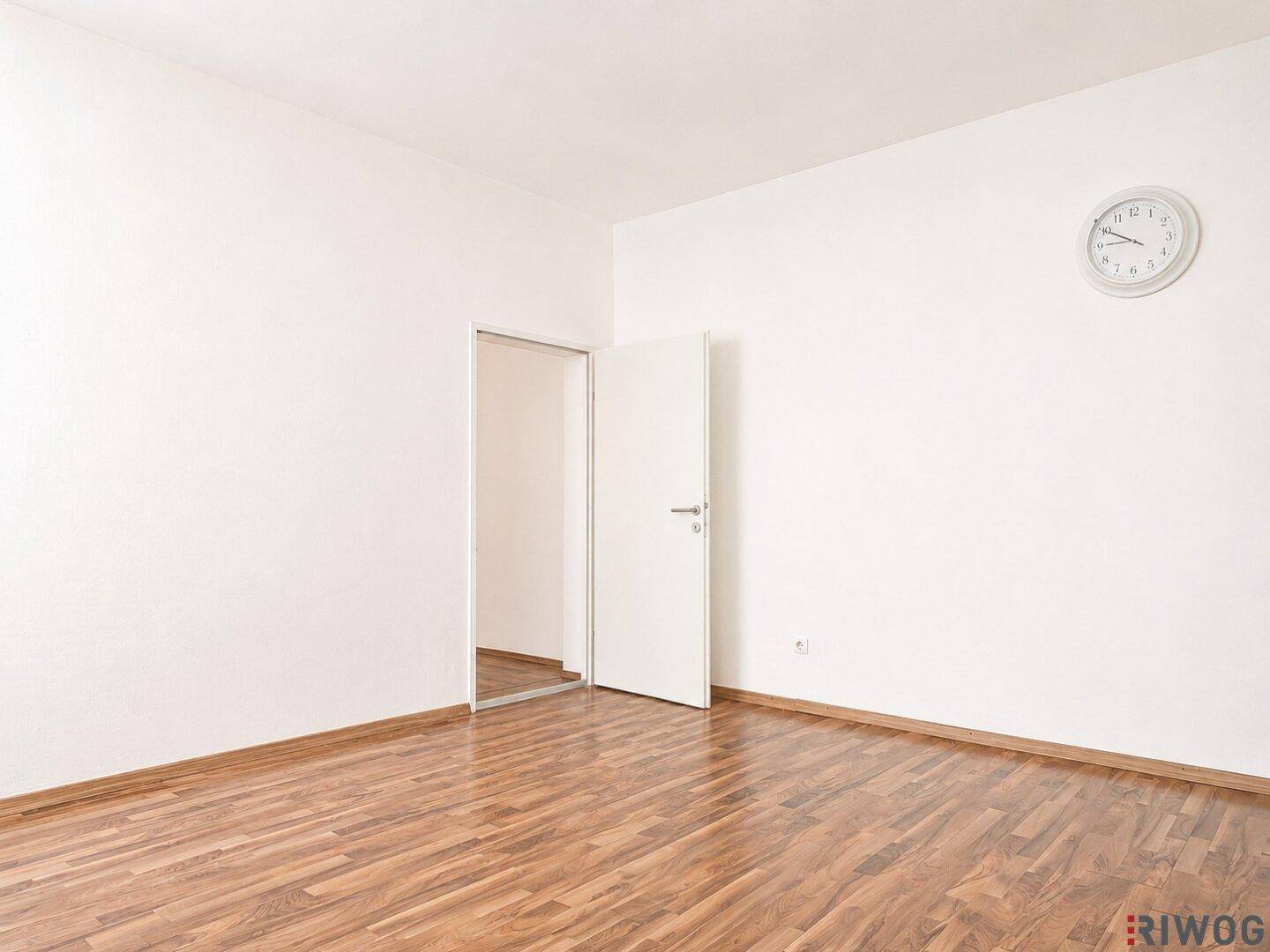 Leerer Raum mit Holzboden und weiß gestrichenen Wänden, bietet vielseitige Nutzungsmöglichkeiten.