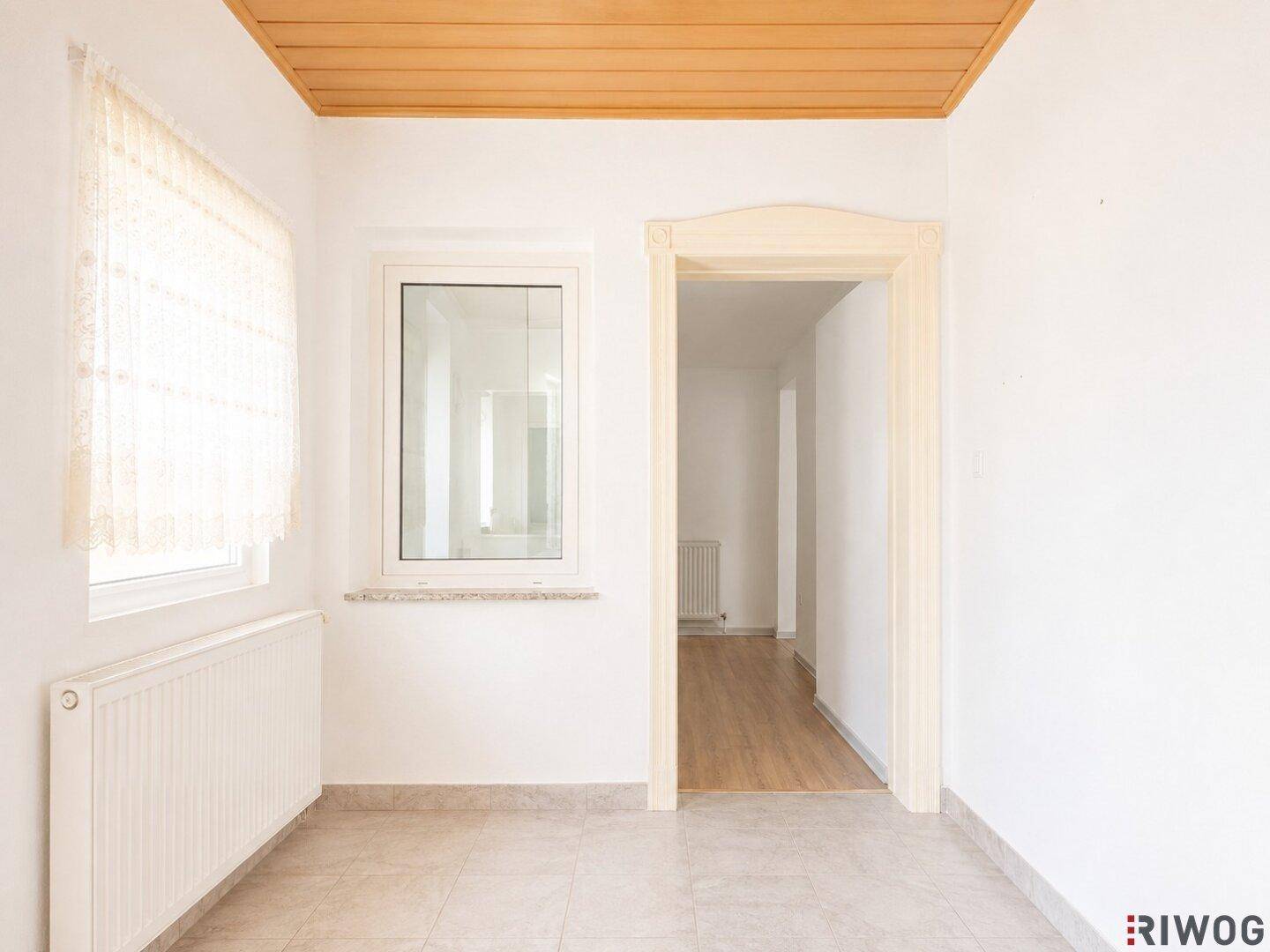 Heller Eingangsbereich mit Fliesenboden und Fenster, das viel Tageslicht hereinlässt.