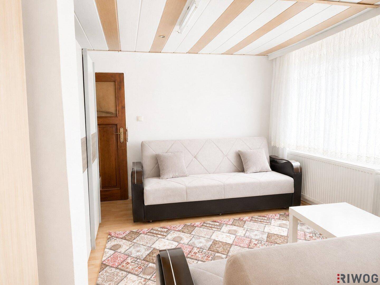 Gemütliches Wohnzimmer mit beigem Sofa und Couchtisch, durchflutet von natürlichem Licht.