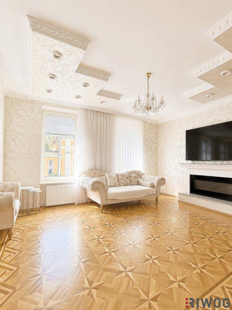 Helles Wohnzimmer mit gemustertem Parkettboden, Kronleuchter und dekorativer Deckenbeleuchtung.