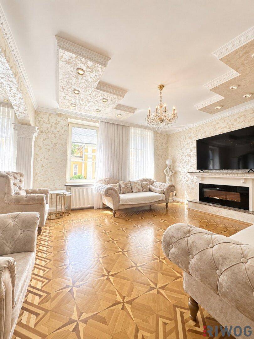 Elegantes Wohnzimmer mit aufwendigem Parkettboden, Stuckdecken und einem modernen Kamin.