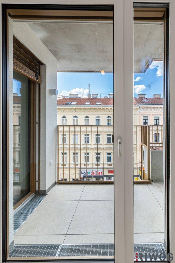 Heller Balkon mit Fliesenboden und Blick auf die umliegenden Gebäude der Stadt.
