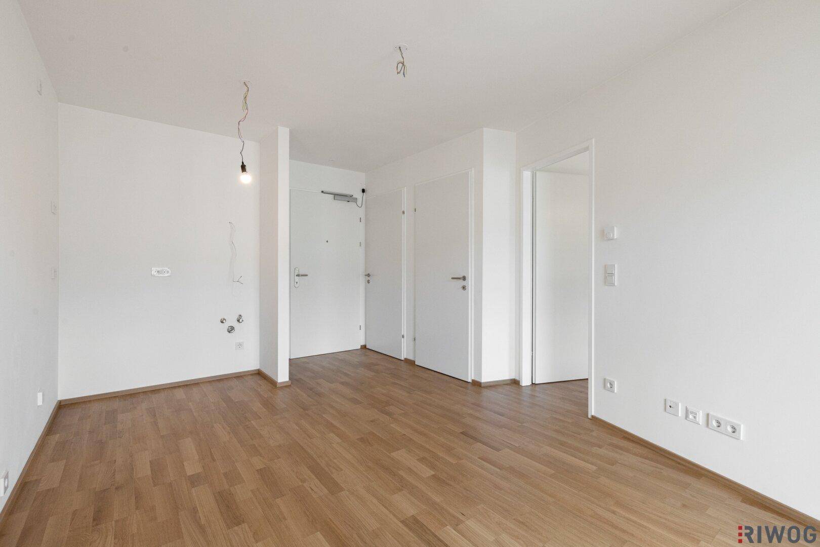 Heller Eingangsbereich mit Holzboden und mehreren Türen zu den angrenzenden Räumen.