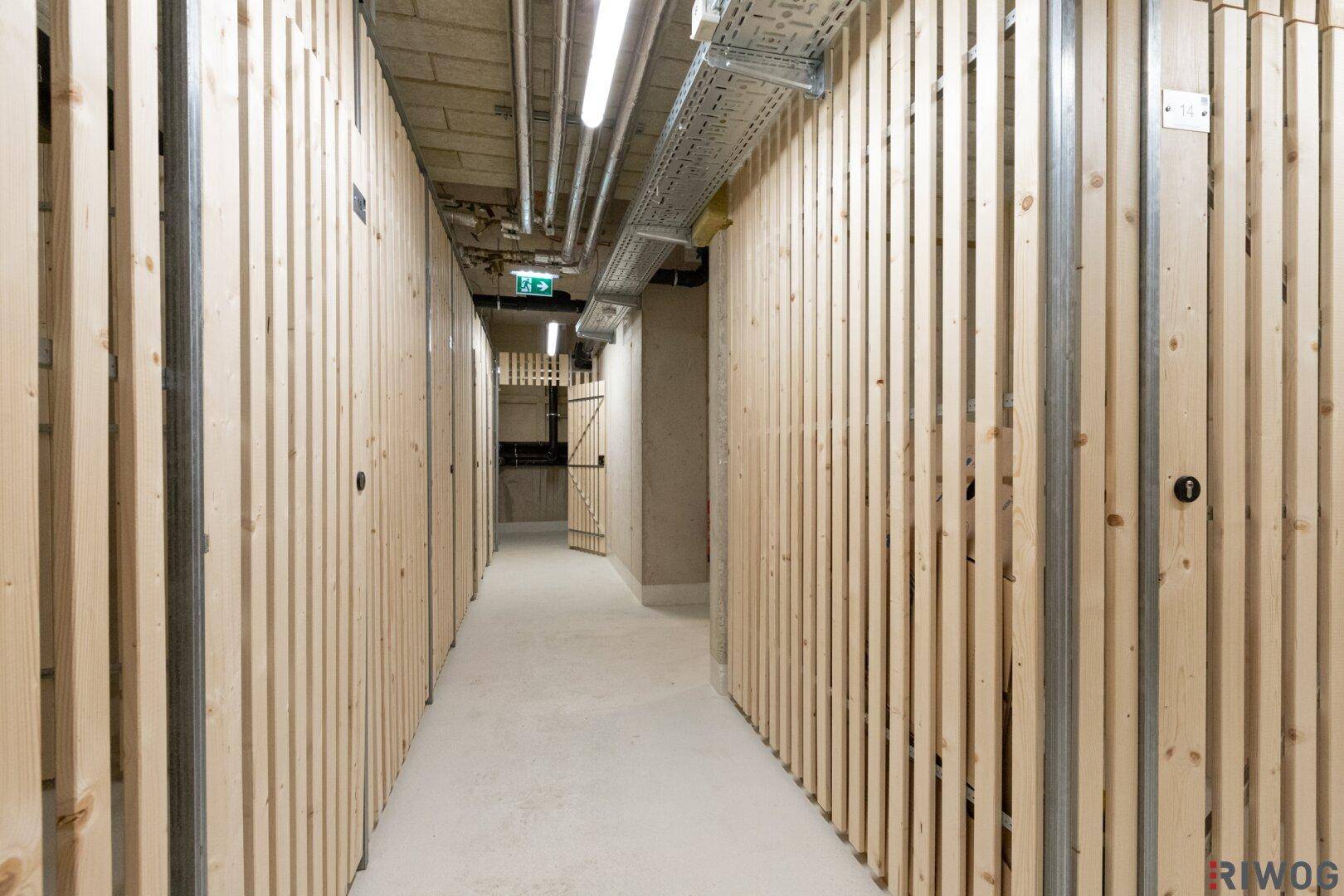 Kellerabteil mit Holzlattenwänden und Betonboden, bietet zusätzlichen Stauraum.