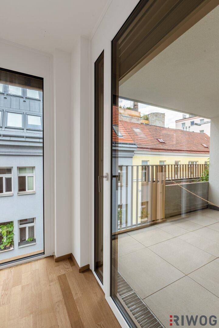 Detailansicht einer Balkontür und eines Fensters mit Blick auf die geflieste Terrasse und Nachbargebäude.
