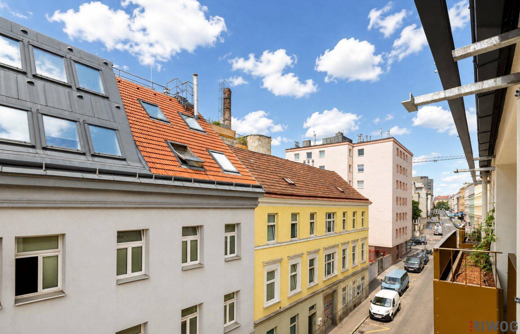 Weitblick von einem Balkon über die Stadt mit verschiedenen Gebäudefassaden und einer Straße.