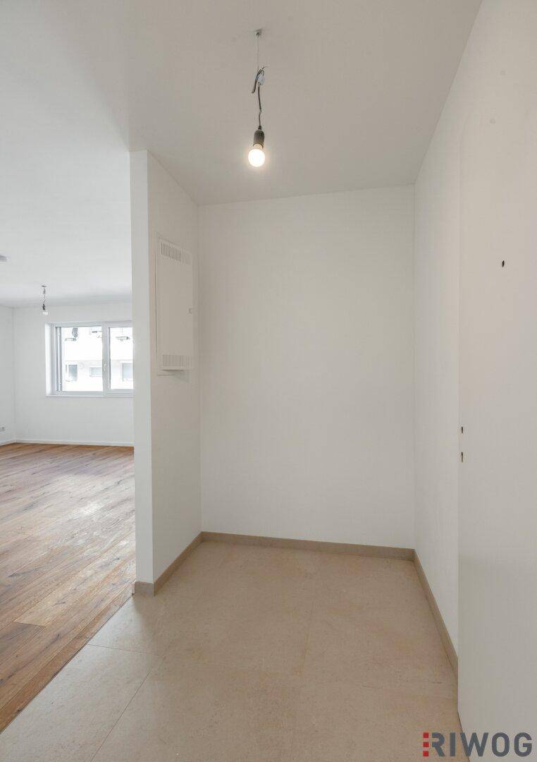 Heller Flurbereich mit Fliesenboden, der in einen Raum mit Holzboden übergeht.