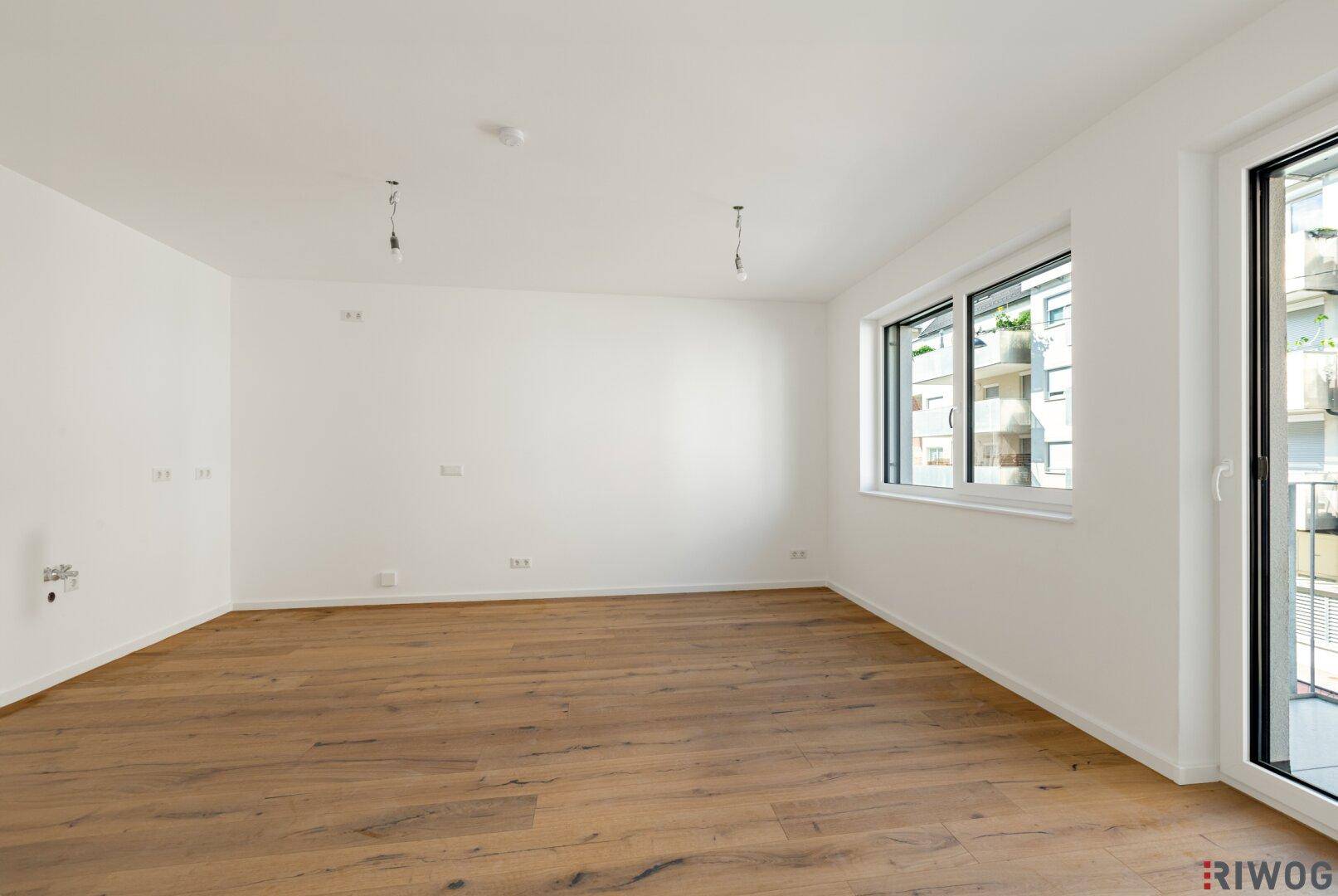 Geräumiges, unmöbliertes Zimmer mit Holzboden und großen Fenstern, bereit zur individuellen Gestaltung.