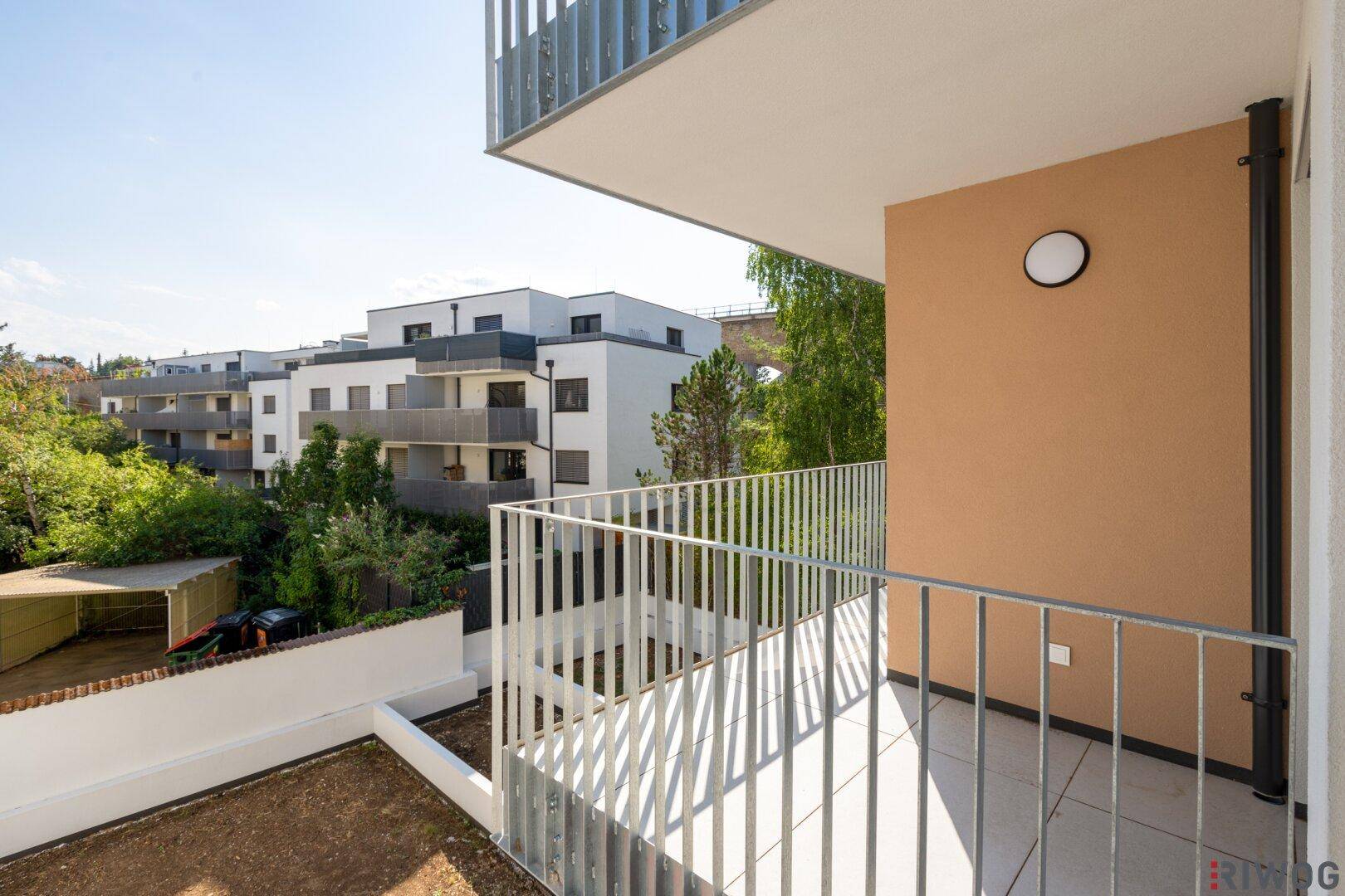 Moderner Balkon mit Metallgeländer und Blick auf die umliegenden Neubauten und Grünflächen.