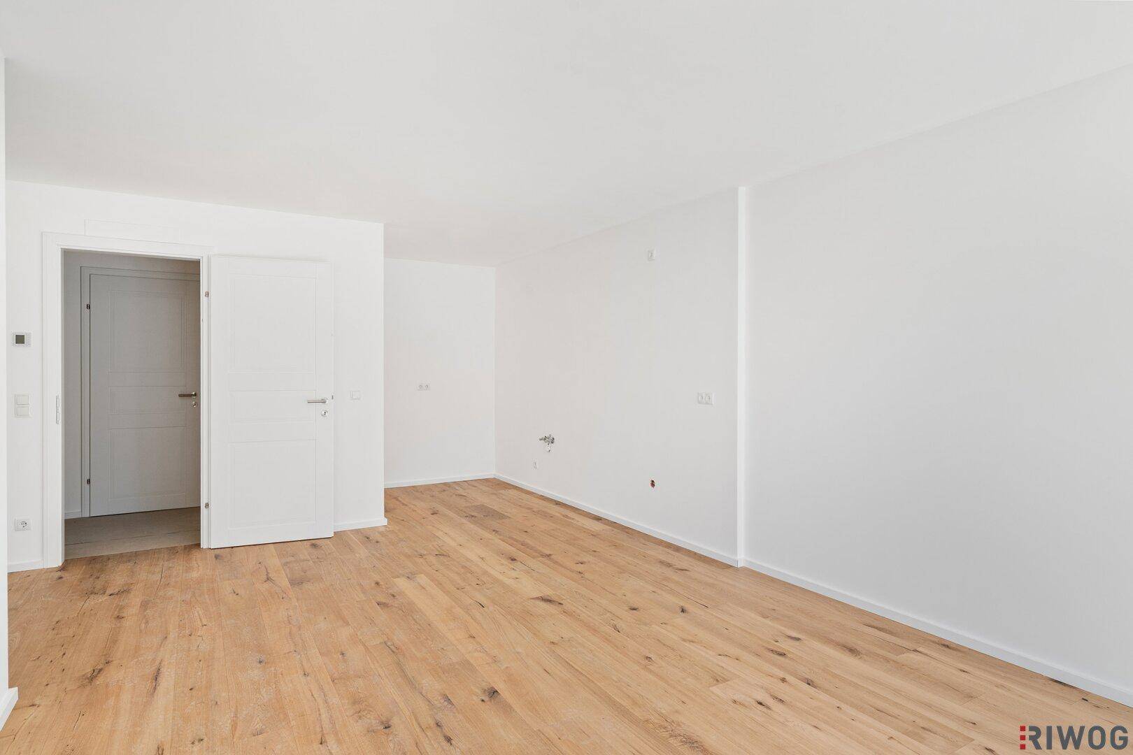 Geräumiger, heller Raum mit Holzboden und weiß gestrichenen Wänden, bereit zur Einrichtung.