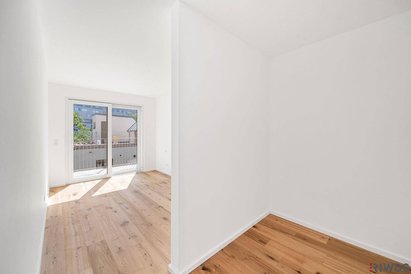 Lichtdurchfluteter Raum mit Holzboden und Schiebetür zum Außenbereich, ideal für flexibles Wohnen.