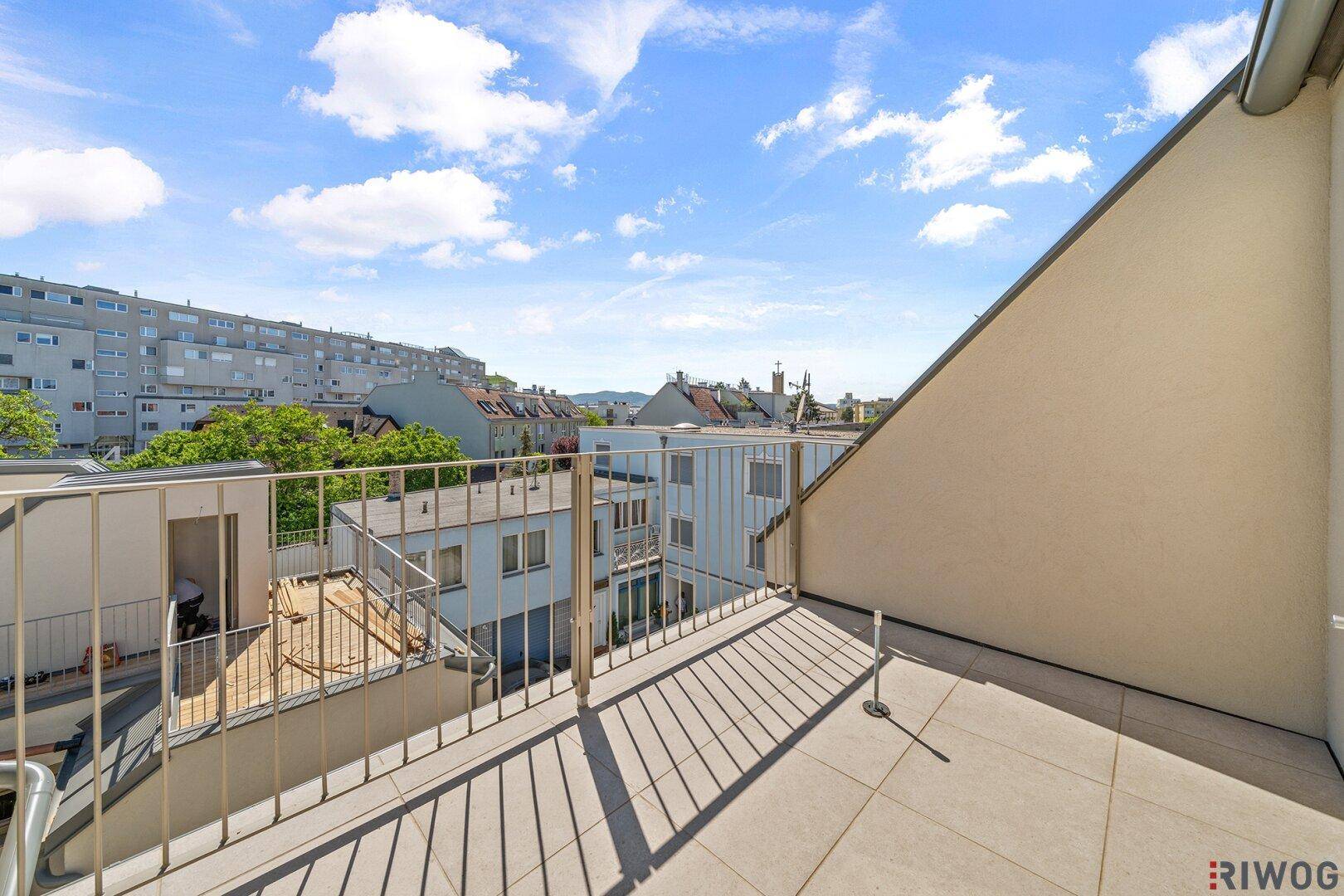 Geräumige Dachterrasse mit Fliesenboden und weitem Blick über die Stadt und umliegende Gebäude.