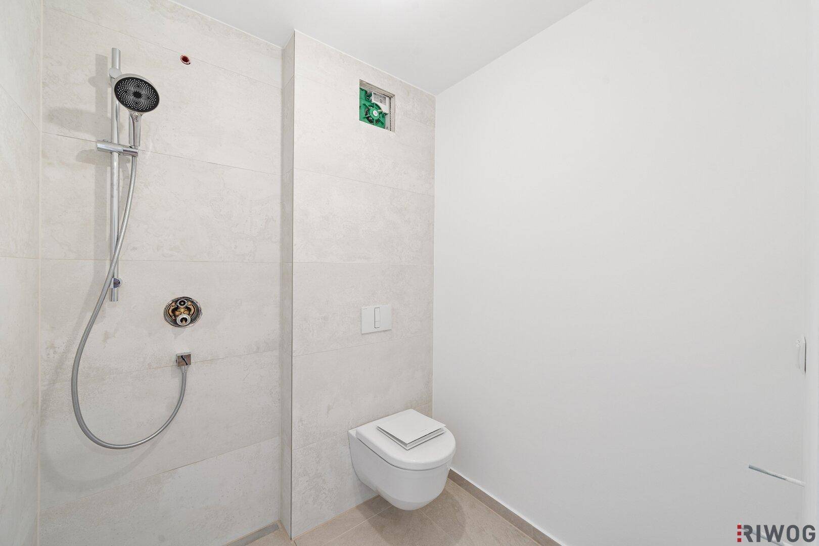 Modernes Badezimmer mit ebenerdiger Dusche und wandhängender Toilette, hell gefliest.