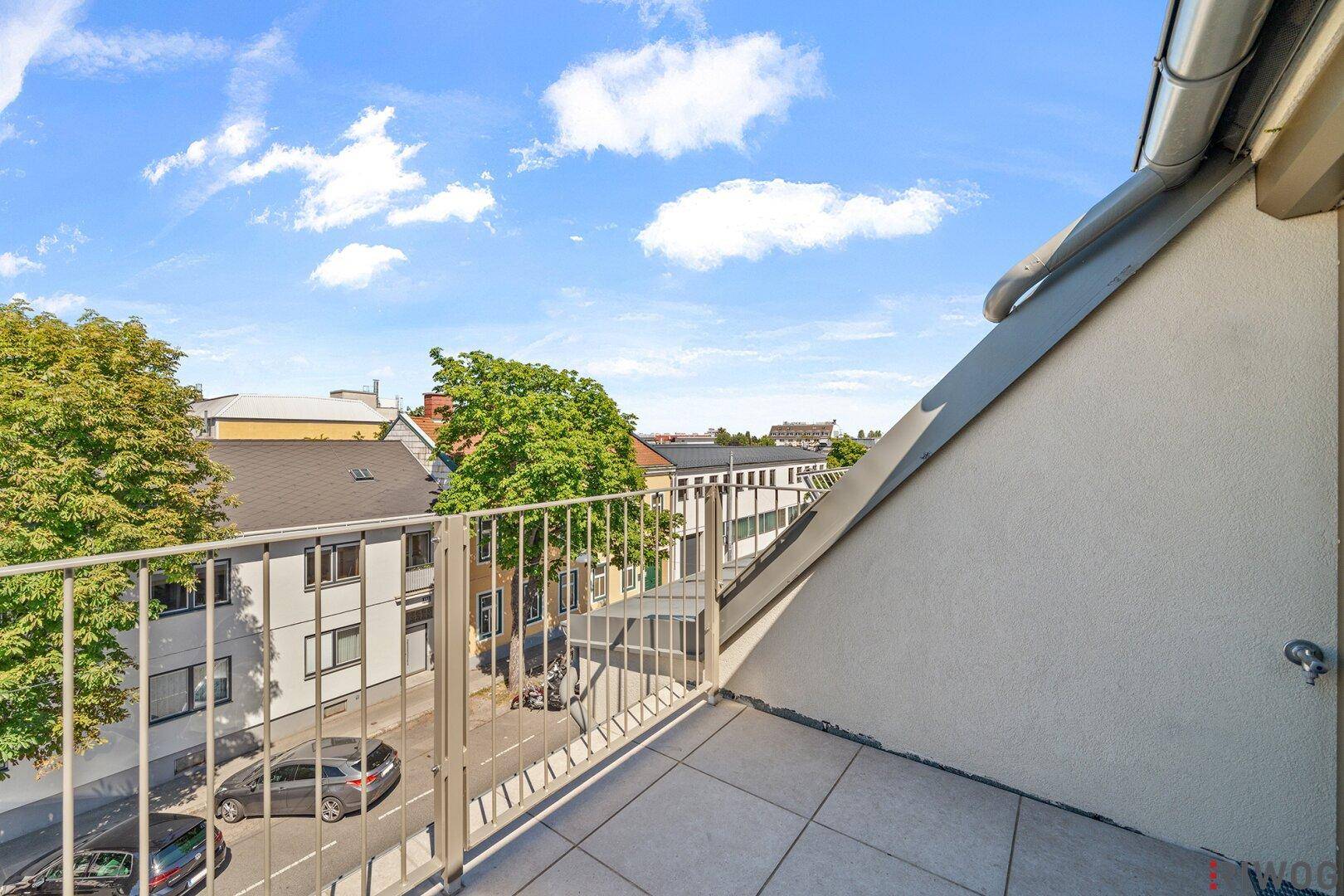 Schmaler Balkon mit Metallgeländer und Blick auf die Straße und umliegende Gebäude.