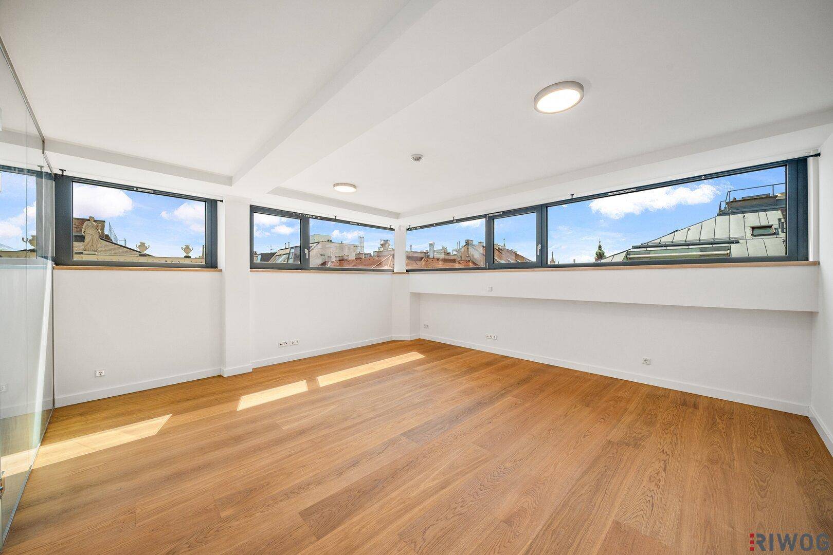 Helles Schlafzimmer mit Holzboden und einer Reihe von Fenstern, die einen weiten Blick bieten.