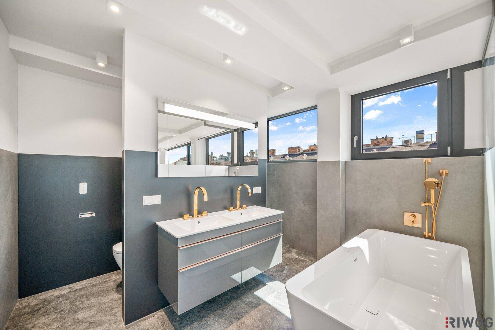 Modernes Badezimmer mit Doppelwaschbecken, Badewanne und Fenster, das viel Licht hereinlässt.