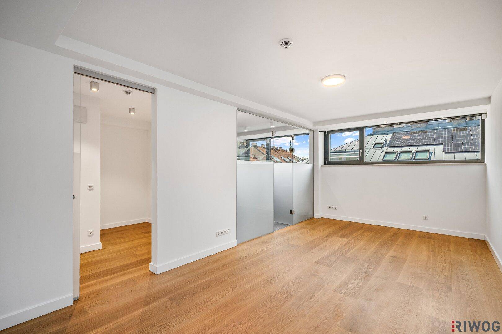 Helles Büro oder Arbeitszimmer mit Holzboden und großen Fenstern, die viel Tageslicht bieten.