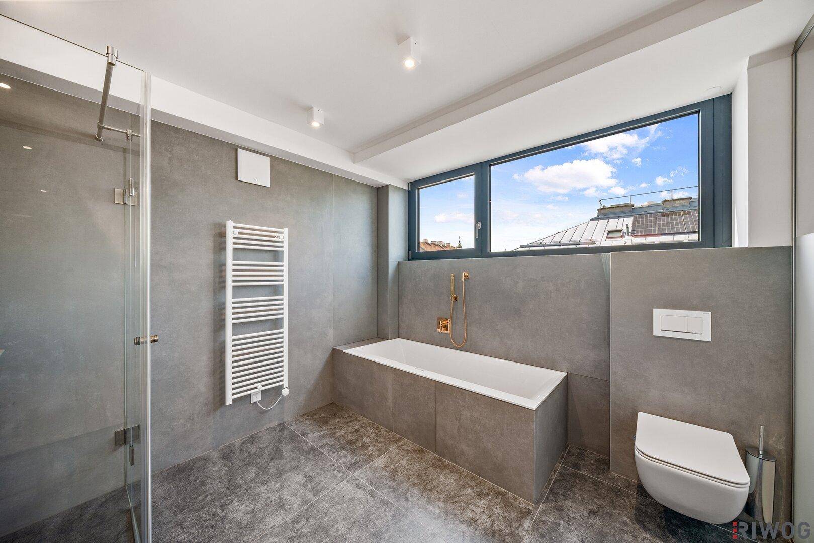 Modernes Badezimmer mit Badewanne, Dusche, WC und beheiztem Handtuchhalter.