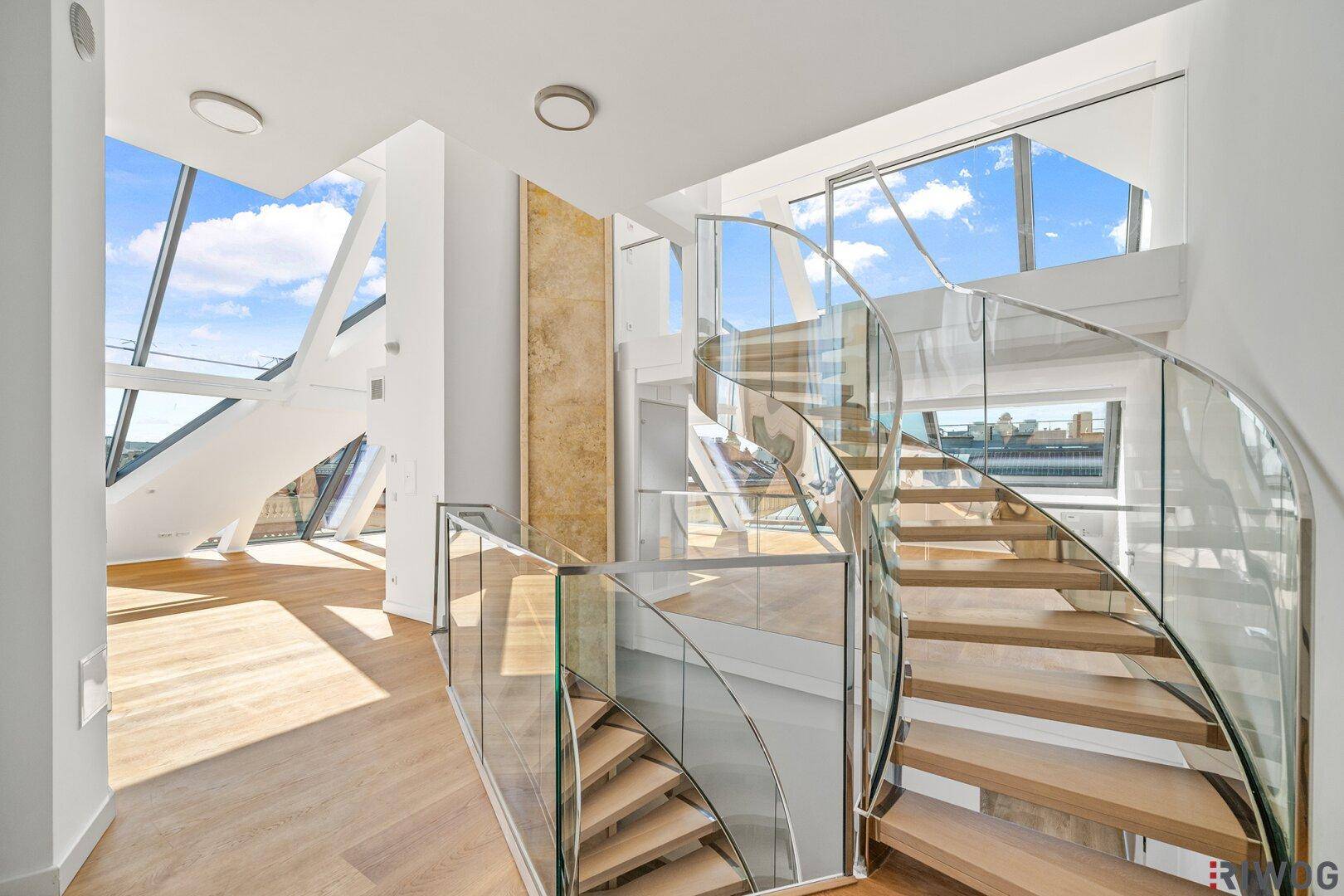 Moderne Wendeltreppe mit Glasgeländer, die verschiedene Ebenen der Wohnung verbindet.