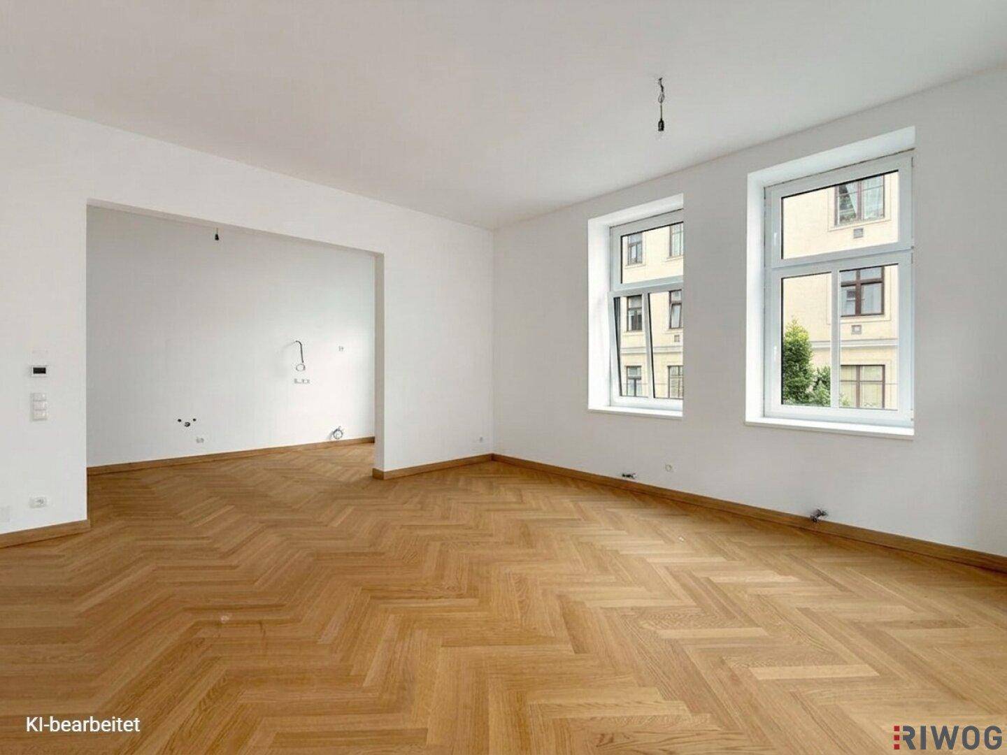 Heller, leerer Raum mit Fischgrätparkett und offenem Durchgang zu einem weiteren Bereich.